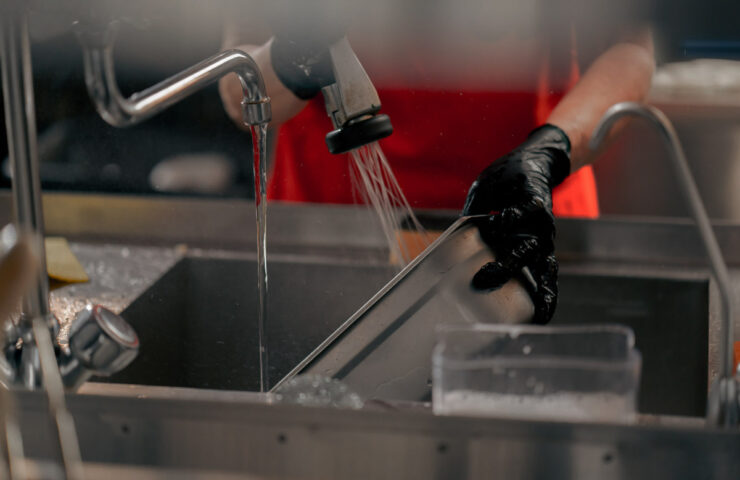 close-up of woman washing dirty dishes in the kitchen after usin